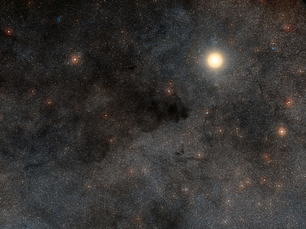 This rich landscape is part of the small constellation of Crux (The Southern Cross). The very bright star is Alpha Crucis, also know as Acrux, one of the four stars that make up the famous cross shape. Most of the upper left part of this image is filled with dark dusty clouds that form part of the huge dark nebula called the Coalsack.