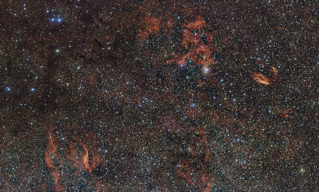 In this huge image of part of the southern constellation of Norma (The Carpenter’s Square) wisps of crimson gas are illuminated by rare, massive stars that have only recently ignited and are still buried deep in thick dust clouds. These scorching-hot, very young stars are only fleeting characters on the cosmic stage and their origins remain mysterious. The vast nebula where these giants were born, known as RCW 106, is captured here in fine detail by ESO’s VLT Survey Telescope (VST), at the Paranal Observatory in Chile. The brightest part appears just above the centre of the image. Many other interesting objects are also captured in this wide-field image. For example the filaments to the right of the image are the remnants of an ancient supernova (SNR G332.4-00.4, also known as RCW 103), and the glowing red filaments at the lower left surround an unusual and very hot star (RCW 104, surrounding the Wolf–Rayet star  WR 75). Patches of dark obscuring dust are also visible across the entire cosmic landscape.