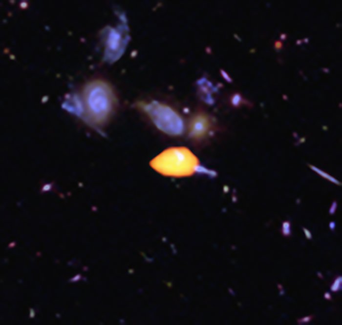 ALMA surveyed the Hubble Ultra Deep Field, uncovering new details of the star-forming history of the Universe. This close-up image reveals one such galaxy (orange), rich in carbon monoxide, showing it is primed for star formation. The blue features are galaxies imaged by Hubble. This image is based on the very deep ALMA survey by Manuel Aravena, Fabian Walter and colleagues, covering about one sixth of the full HUDF area.