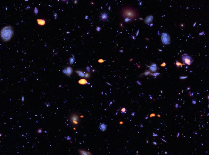 A trove of galaxies, rich in carbon monoxide (indicating star-forming potential) were imaged by ALMA (orange) in the Hubble Ultra Deep Field. The blue features are galaxies imaged by Hubble.This image is based on the very deep ALMA survey by Manuel Aravena, Fabian Walter and colleagues, covering about one sixth of the full HUDF area.