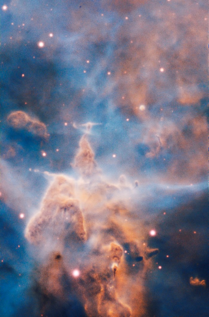 This craggy fantasy mountaintop enshrouded by wispy clouds looks like a bizarre landscape. But it is indeed a pillar of gas and dust, three light-years tall, which is being eaten away by the brilliant light from nearby bright stars. The pillar is also being assaulted from within, as infant stars buried inside it fire off jets of gas that can be seen streaming from towering peaks.