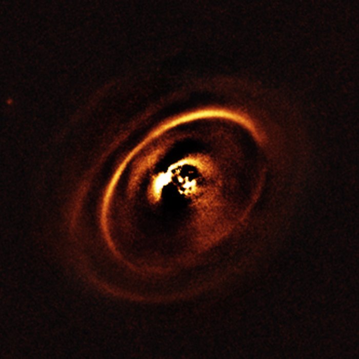 Using the ESO’s SPHERE instrument at the Very Large Telescope, a team of astronomer observed the planetary disc surrounding the star RXJ1615 which lies in the constellation of Scorpius, 600 light-years from Earth. The observations show a complex system of concentric rings surrounding the young star, forming a shape resembling a titanic version of the rings that encircle Saturn. Such an intricate sculpting of rings in a protoplanetary disc has only been imaged a handful of times before. The central parts of the image appears dark because SPHERE blocks out the light from the brilliant central star to reveal the much fainter structures surrounding it.